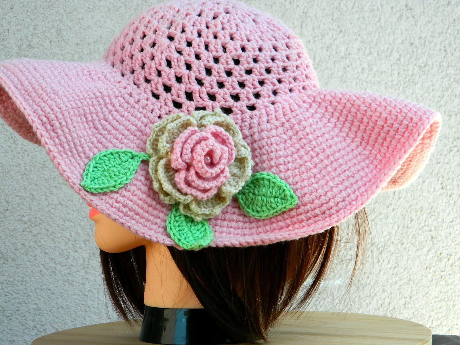 Handgehäkelter rosa Sonnenhut mit Lochmuster-Krone und einer gehäkelten Rose mit grünen Blättern
